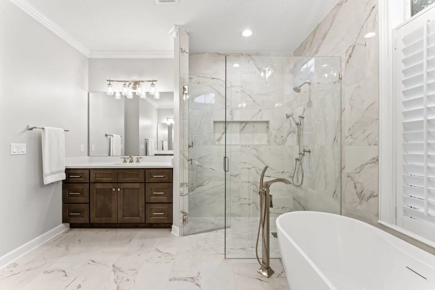 Jacksonville Beach bathroom with a marble shower, freestanding tub and plantation shutters