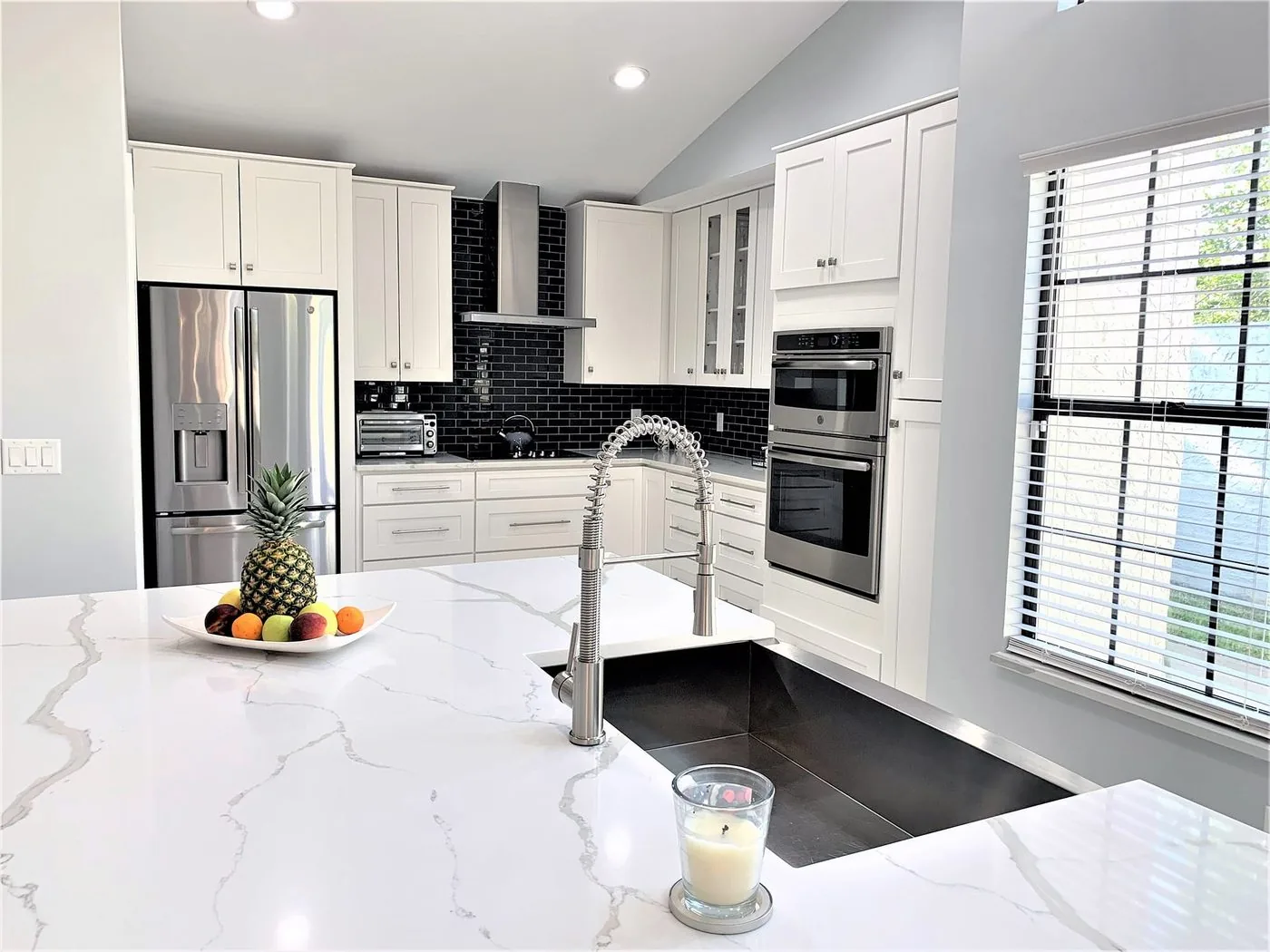 Miramar kitchen with a waterfall counter, black backsplash and stainless appliances